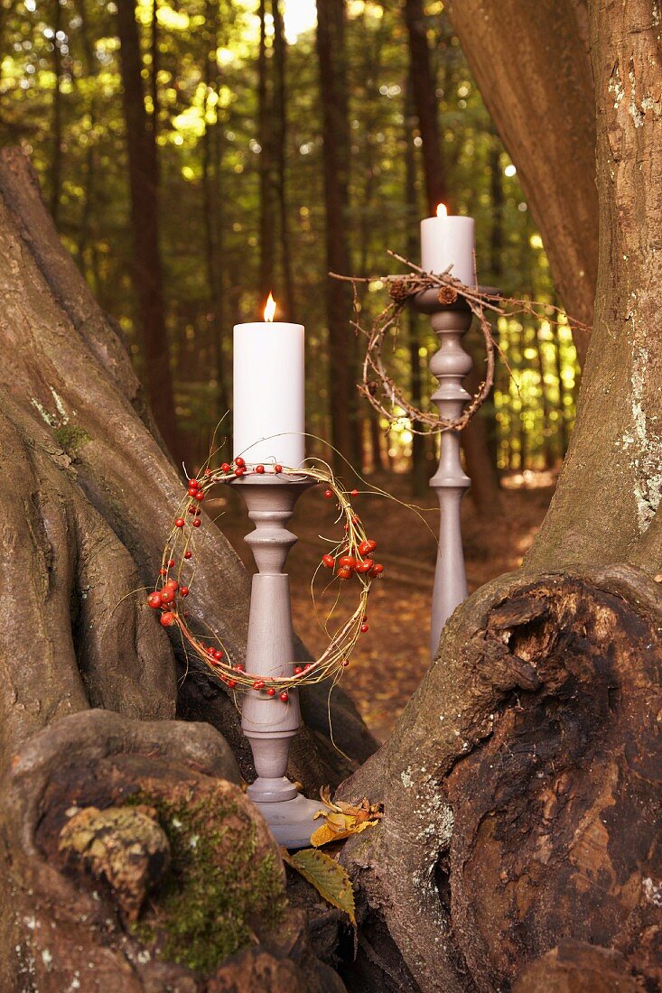 Kerzen mit Beerenkränzchen im herbstlichen Wald