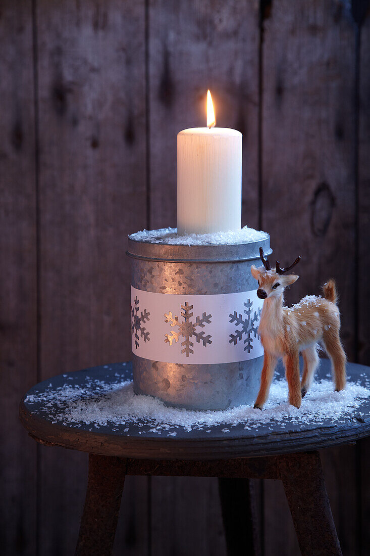 Christmas decoration - animal ornament and lit Christmas candle on rustic stool