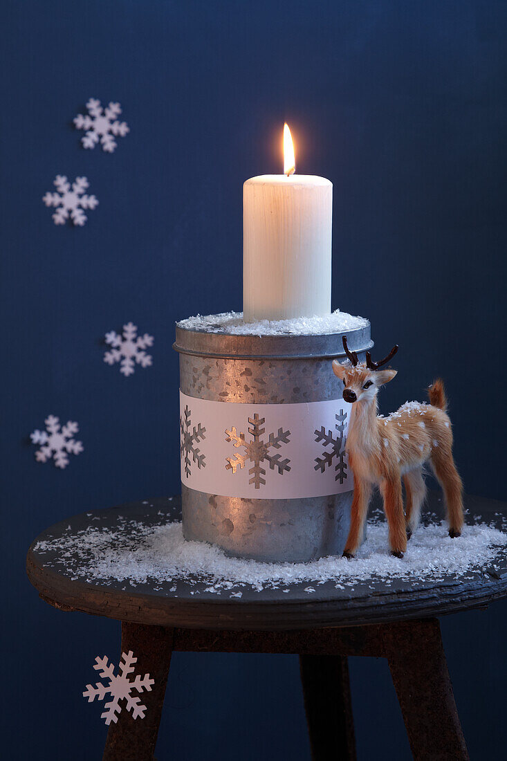 Christmas decoration - animal ornament and lit Christmas candle on rustic stool