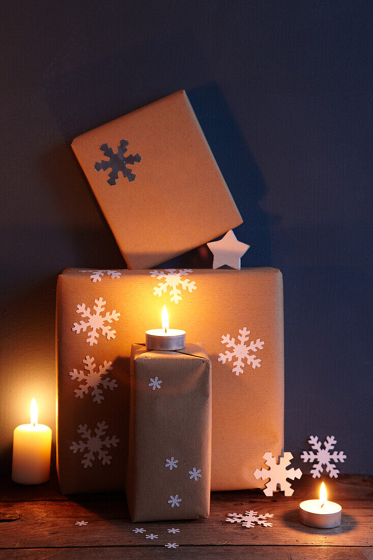 Lit tealights and Christmas presents against blue-painted wall