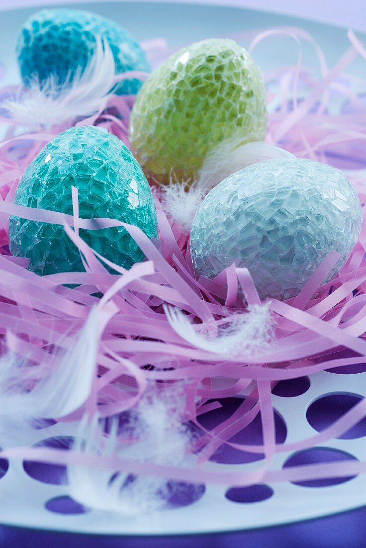 Pastel coloured Easter eggs lying on pink ribbons