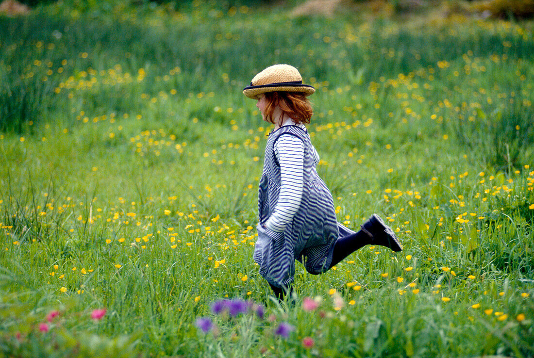 Child running across a meadow of flowers