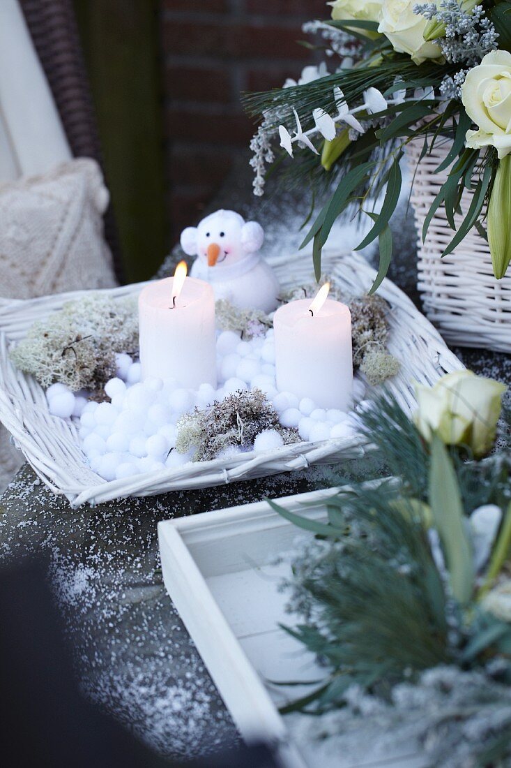 Winterdeko mit Kerzen, Schneemann und Blumen