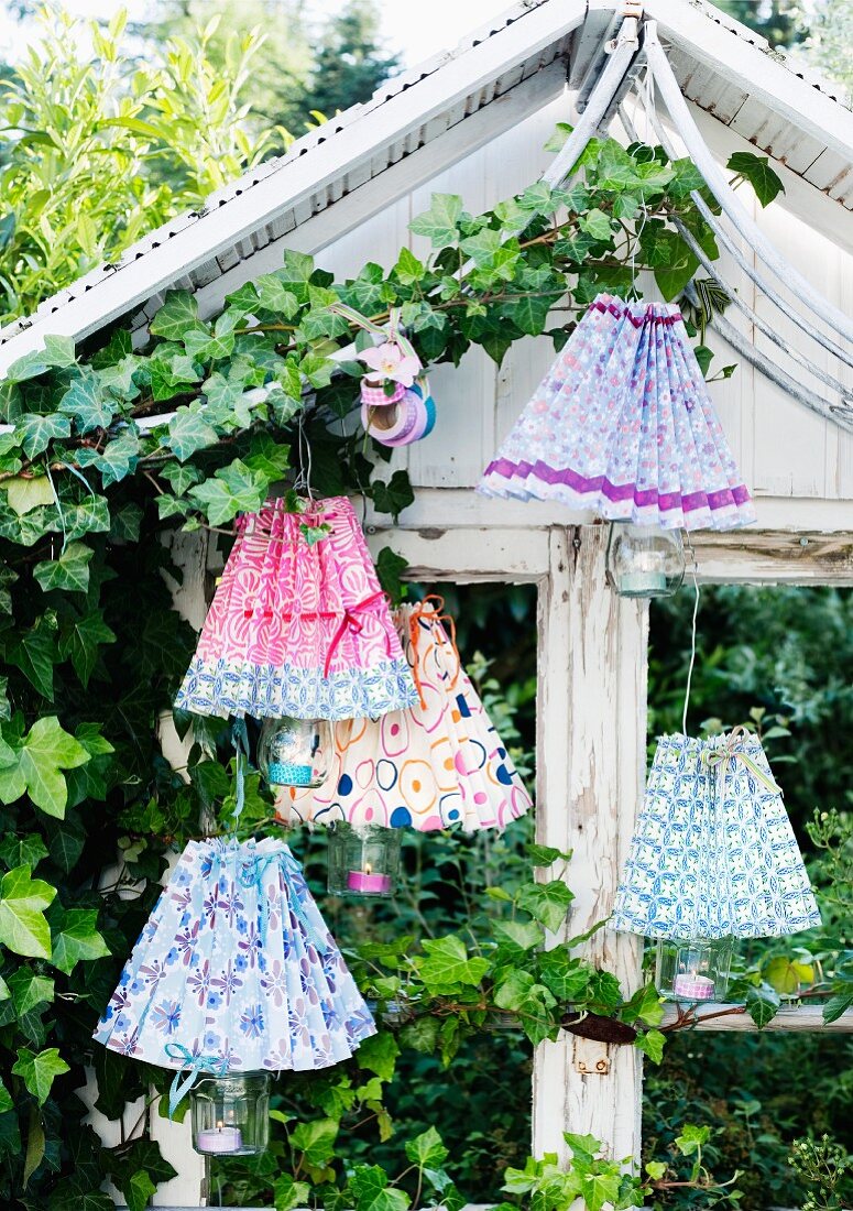 Hand-crafted lampshades covering tealight holders in garden