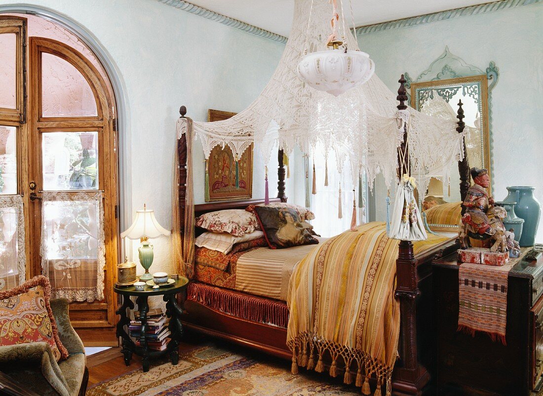 Antikes Himmelbett mit transparentem Baldachin aus Spitze im stilgemixten Schlafzimmer mit orientalischen Einflüssen