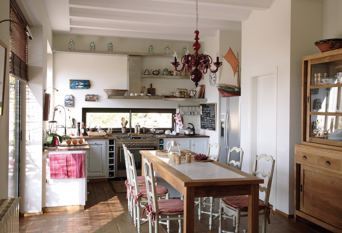 Sunny kitchen-dining room in Mediterranean country house style with turned wooden chairs at modern wooden table