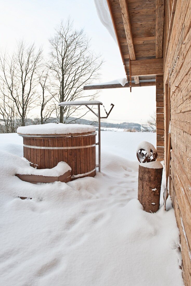 Brunnen vor Holzhaus in Winterstimmung