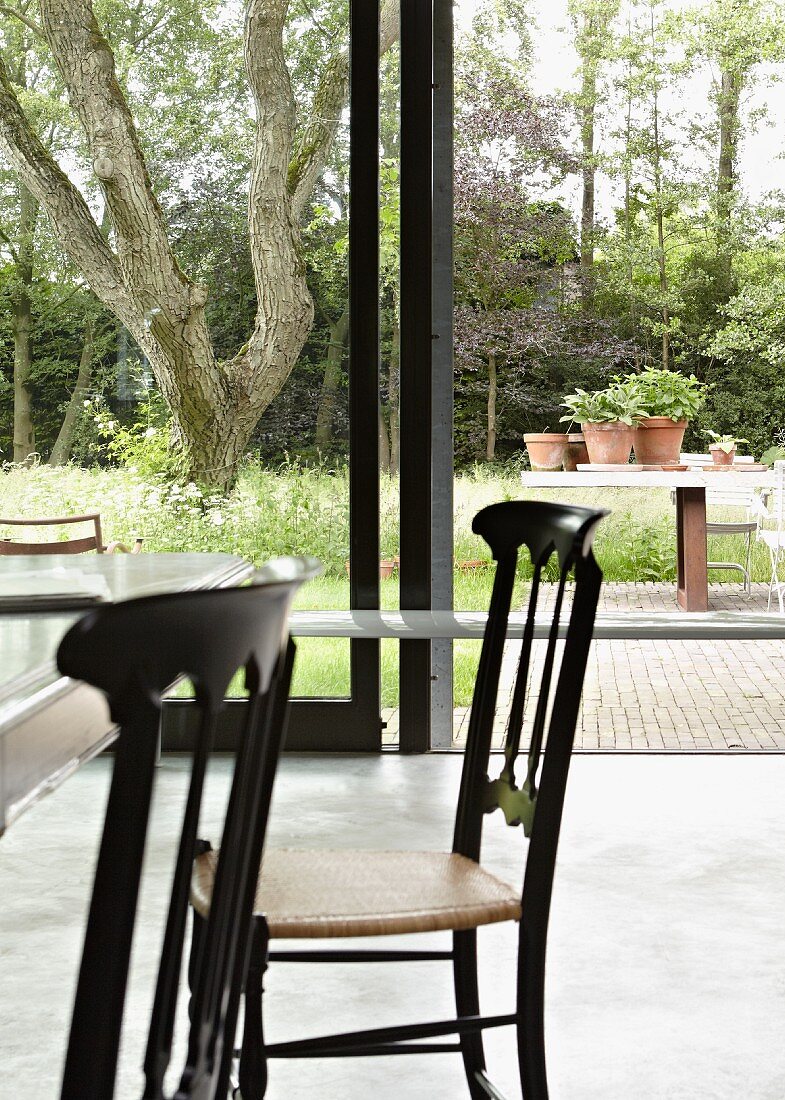 Esstisch mit Chiavari-Stühlen vor Glasschiebetür zum Garten