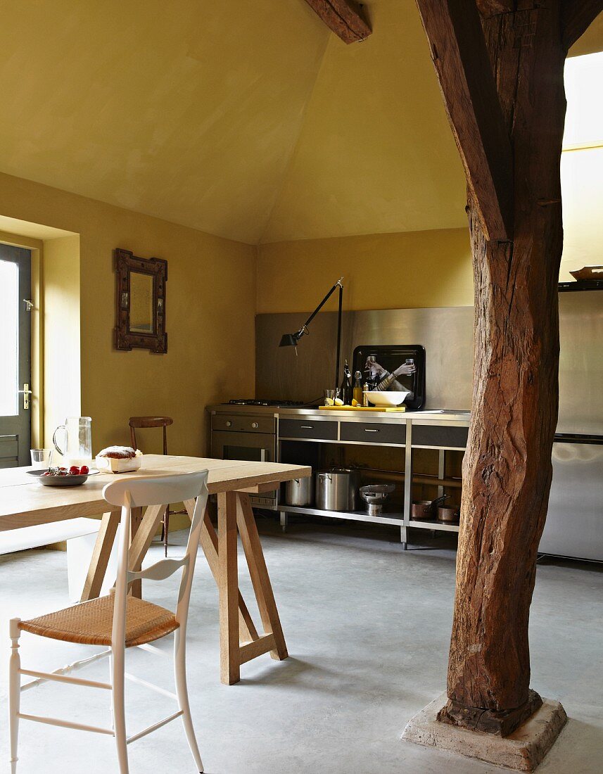 Wohnküche mit gelben Wänden und einer Holzstütze