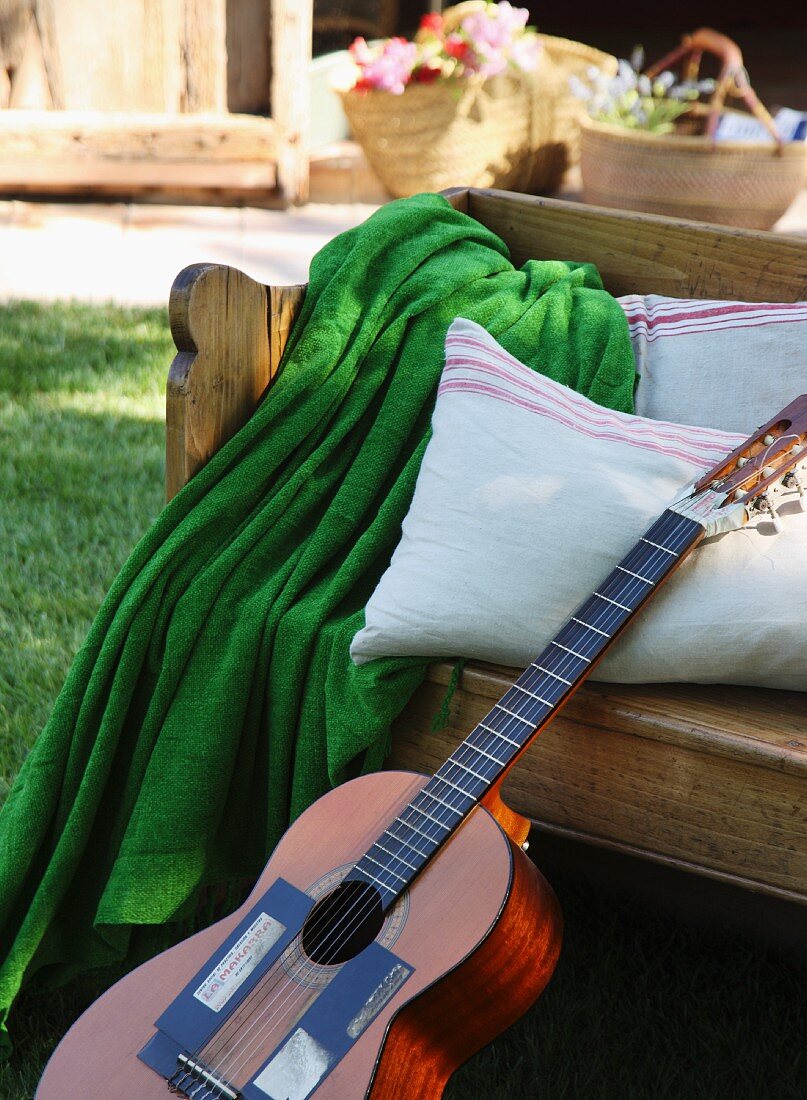 Holzbank mit Decke, Kissen und Gitarre