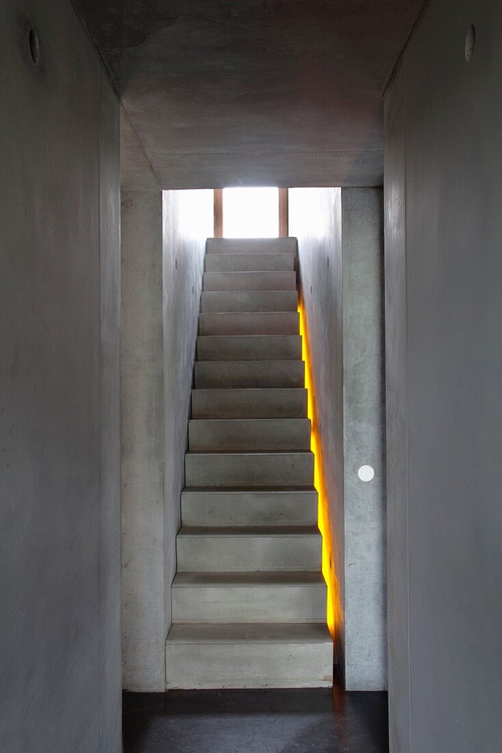 Minimalistischer Treppenaufgang - komplett aus Sichtbeton mit gelbem Lichtstreifen zwischen Wand und Treppenwange