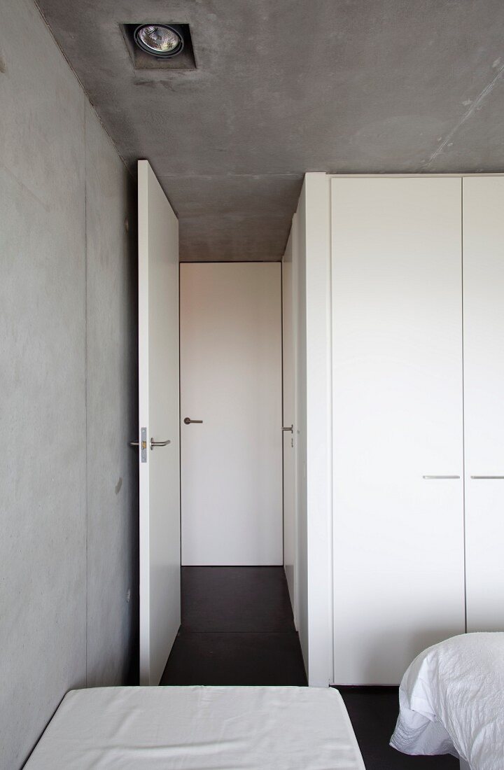 White decor and exposed concrete in austere, minimalist bedroom