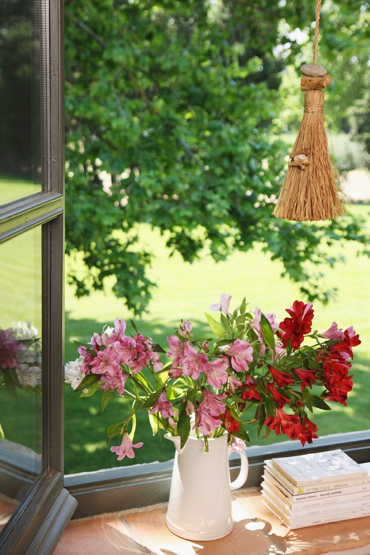 Krug mit Lilien auf der Fensterbank
