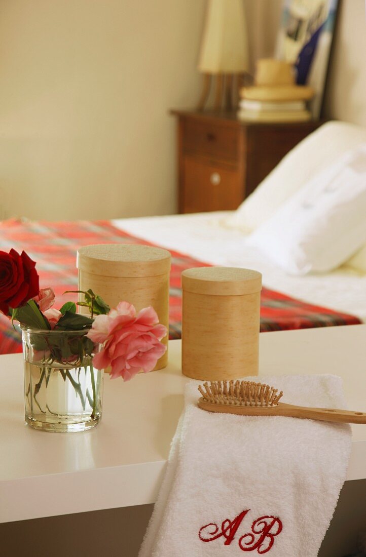 Ablage mit Rosen, Handtuch, Haarbürste und Dosen in einem Schlafzimmer