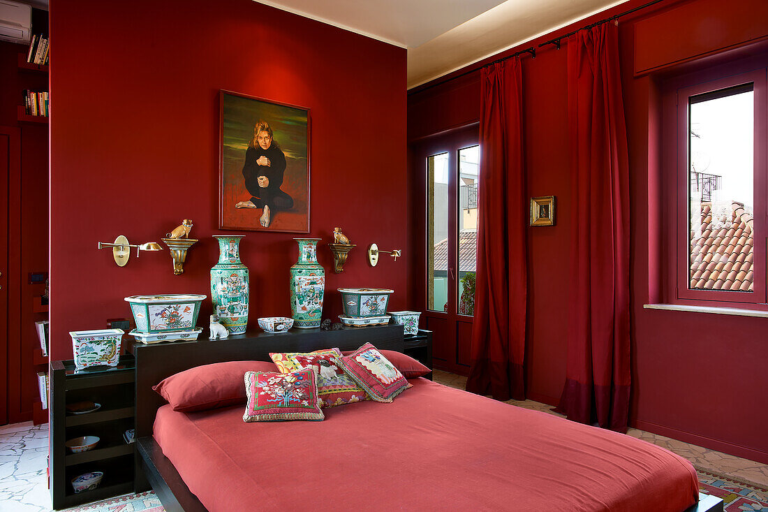 Red bedroom - double bed in front of Chinese vases on cabinet against red partition and floor-length red curtains