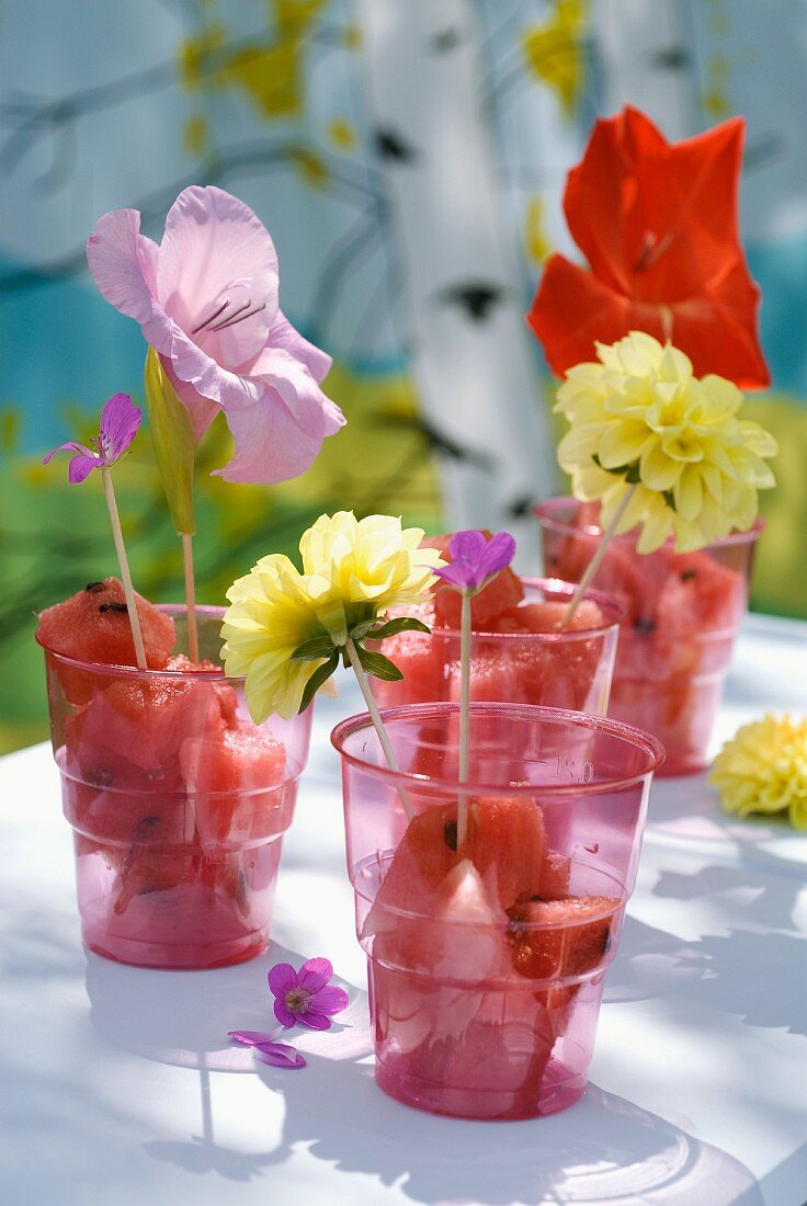 Wassermelon in Plastikbechern mit Blumen dekoriert