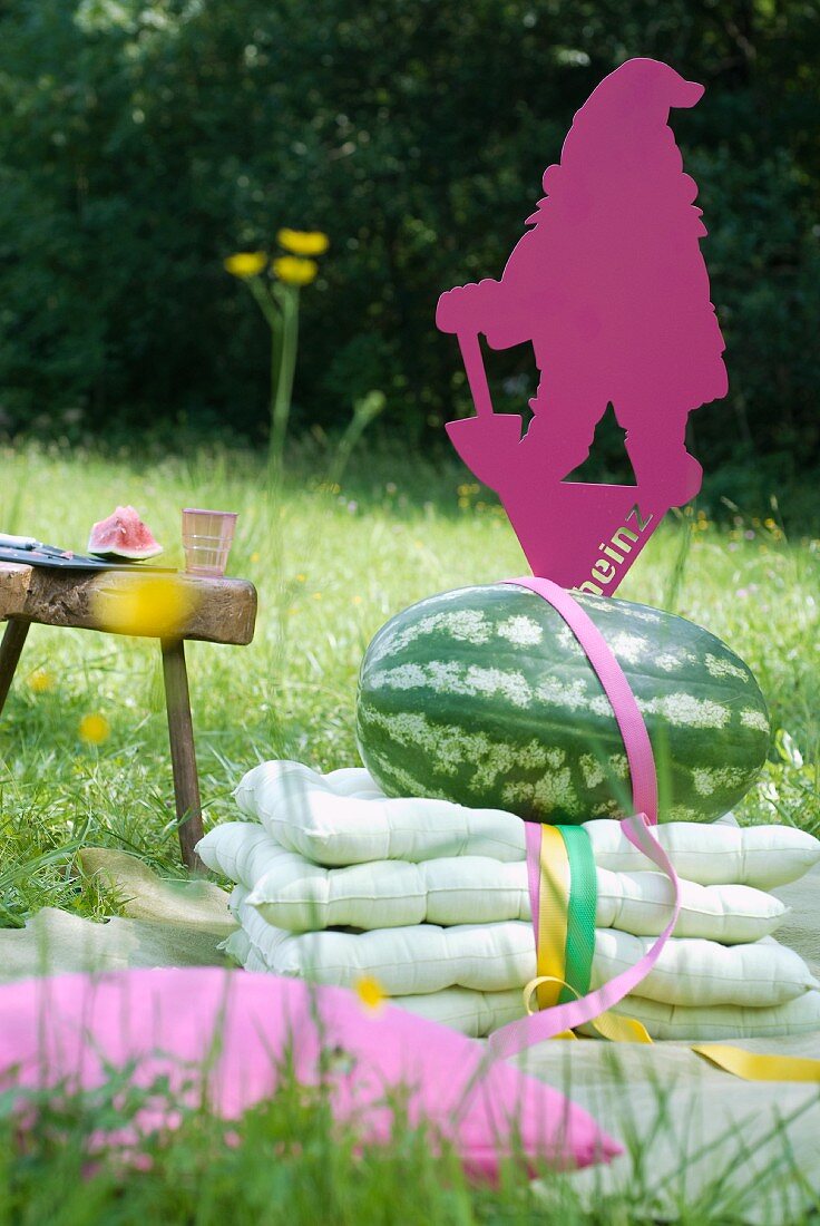 Cushions, water melon and brightly coloured garden gnome shaped from sheet metal