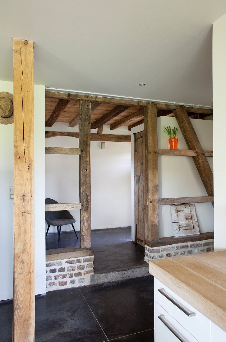 Detail of renovated half-timbered house with black tiled floor in open-plan interior and view into foyer