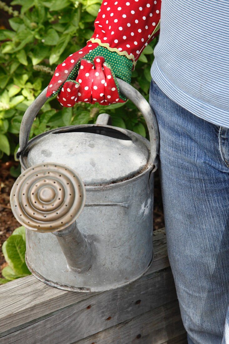 A woman with a watering can in a garden