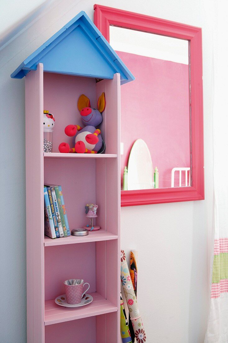Rosa lackiertes Holzregal an Wand neben Spiegel mit pinkfarbenem Rahmen