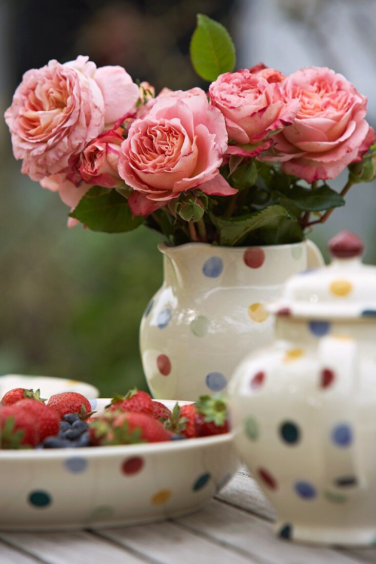 Rosenstrauss und Erdbeeren auf Gartentisch