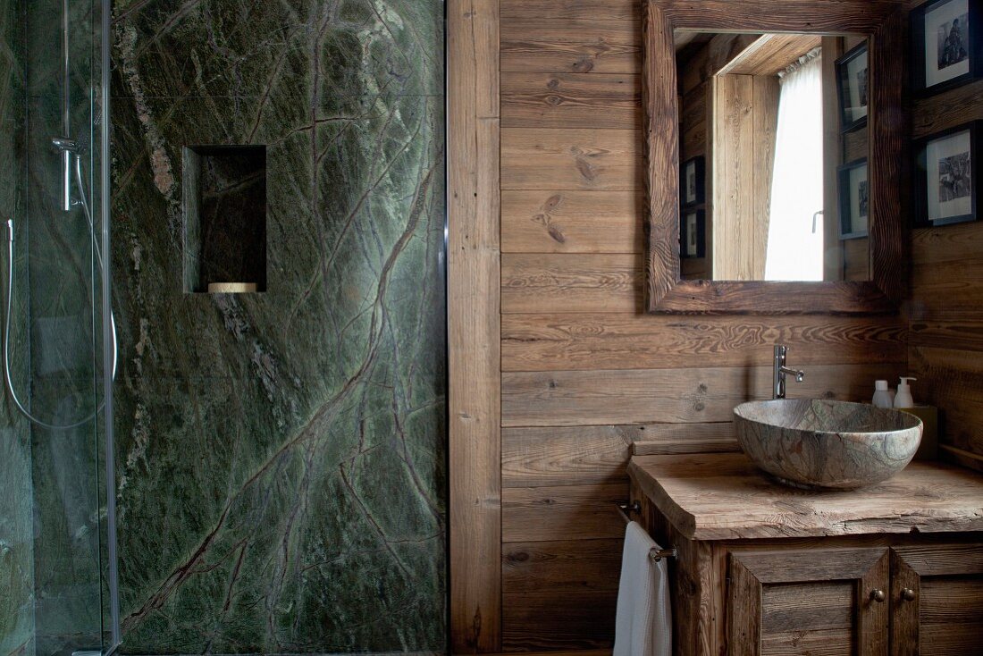 Steinwand mit Wandnische im Duschbereich eines rustikalen Badezimmers mit Steinwaschschüssel und Holzwaschtisch