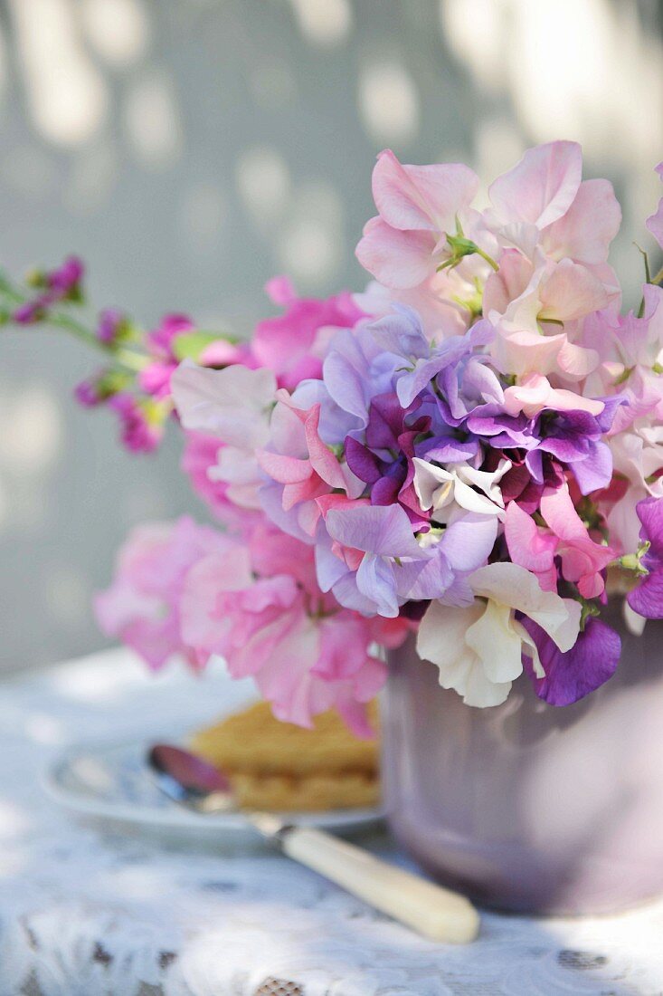 Verschiedenfarbige Blumen im Keramiktopf auf dem Frühstückstisch