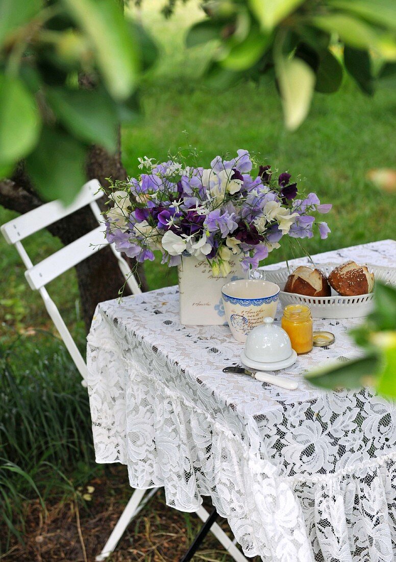 Gedeckter Frühstückstisch mit Blumenstrauss im Garten