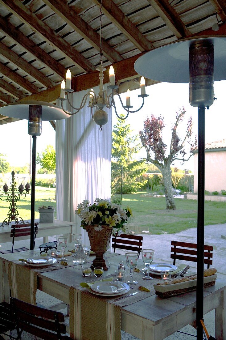 Festively set table on roofed terrace with patio heater and view of garden