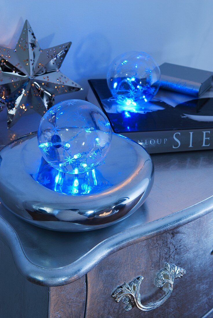 Transparent bauble on decorative silver dish and silver star on vintage chest of drawers