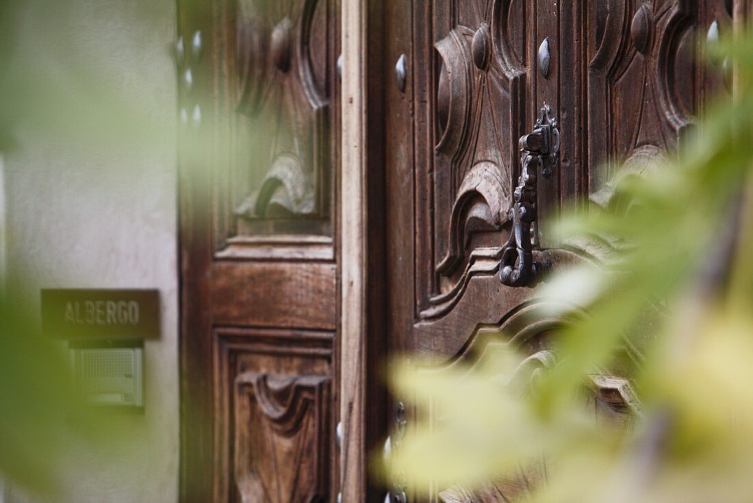 Carved wooden front door with modern doorbell on house facade