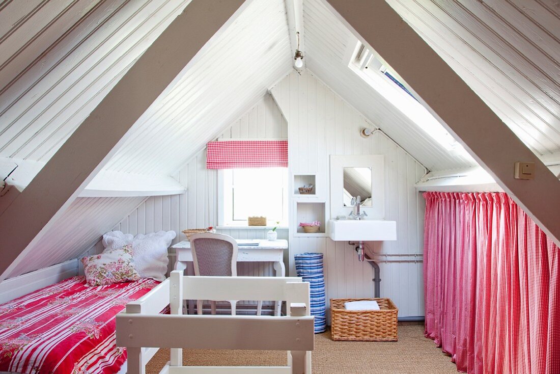 Room with bed, desk, sink and storage area below gable ceiling