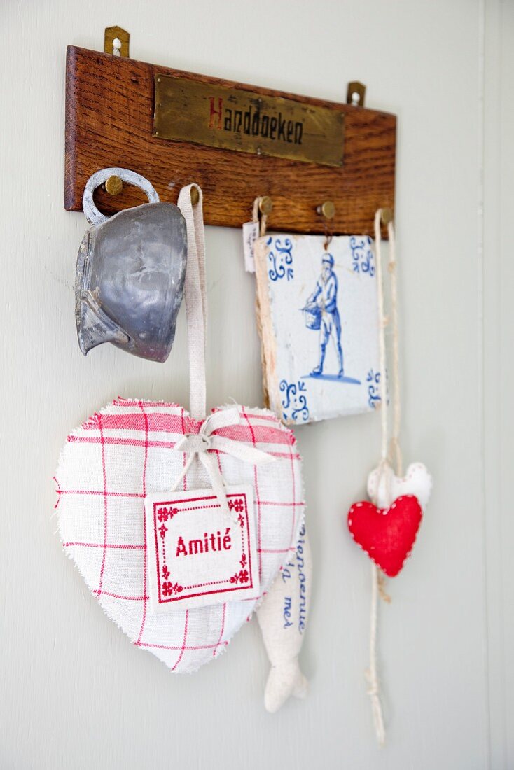 Fabric love hearts, tile coaster and old cup hanging from wooden peg board