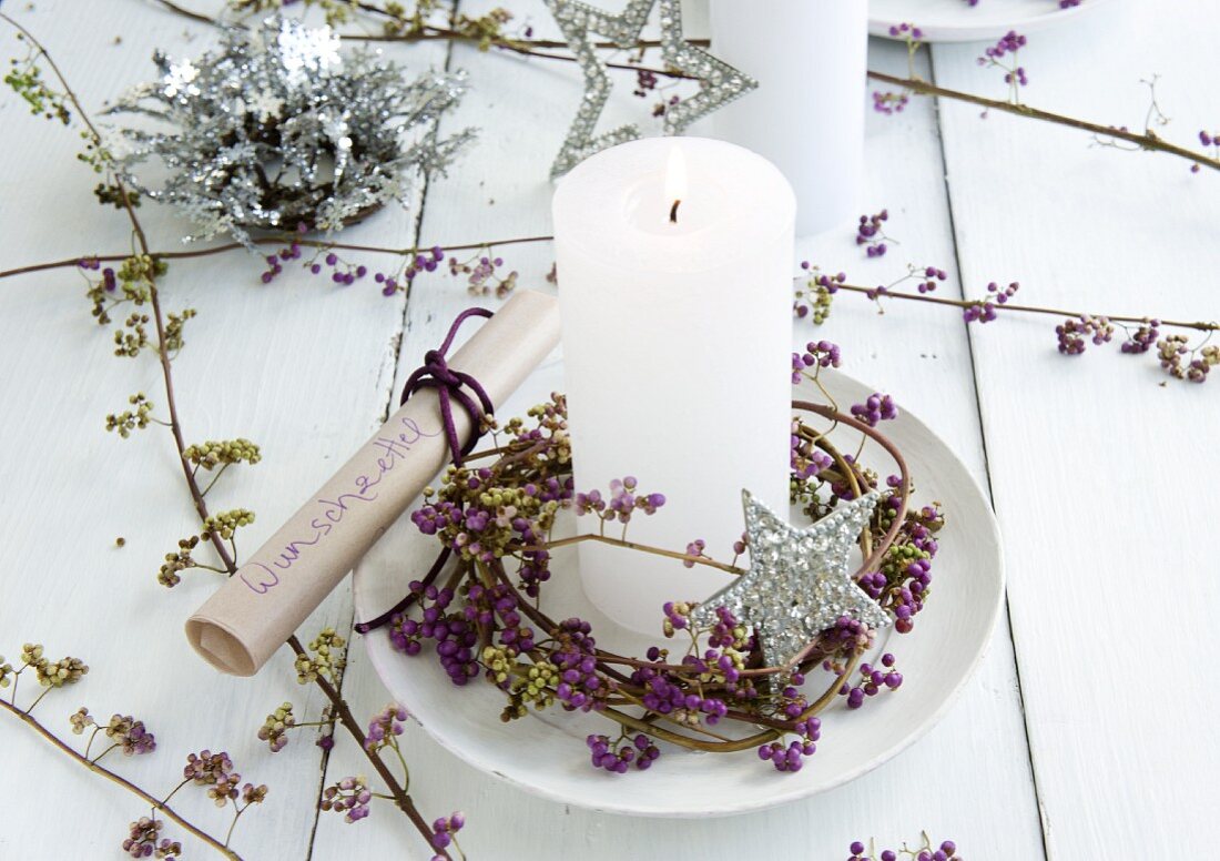 Lit candle on saucer in wreath of callicarpa with Christmas decorations