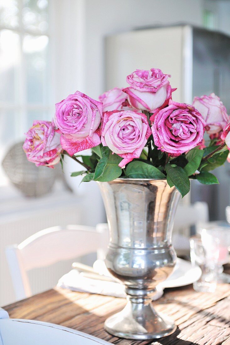 Silver vase of pink roses on dining table