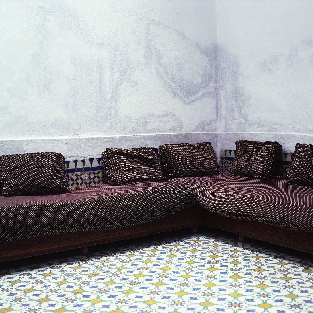 A brown corner sofa in a room with a white tiled floor