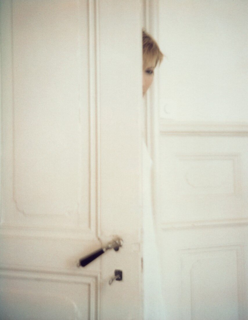 A young woman behind a door