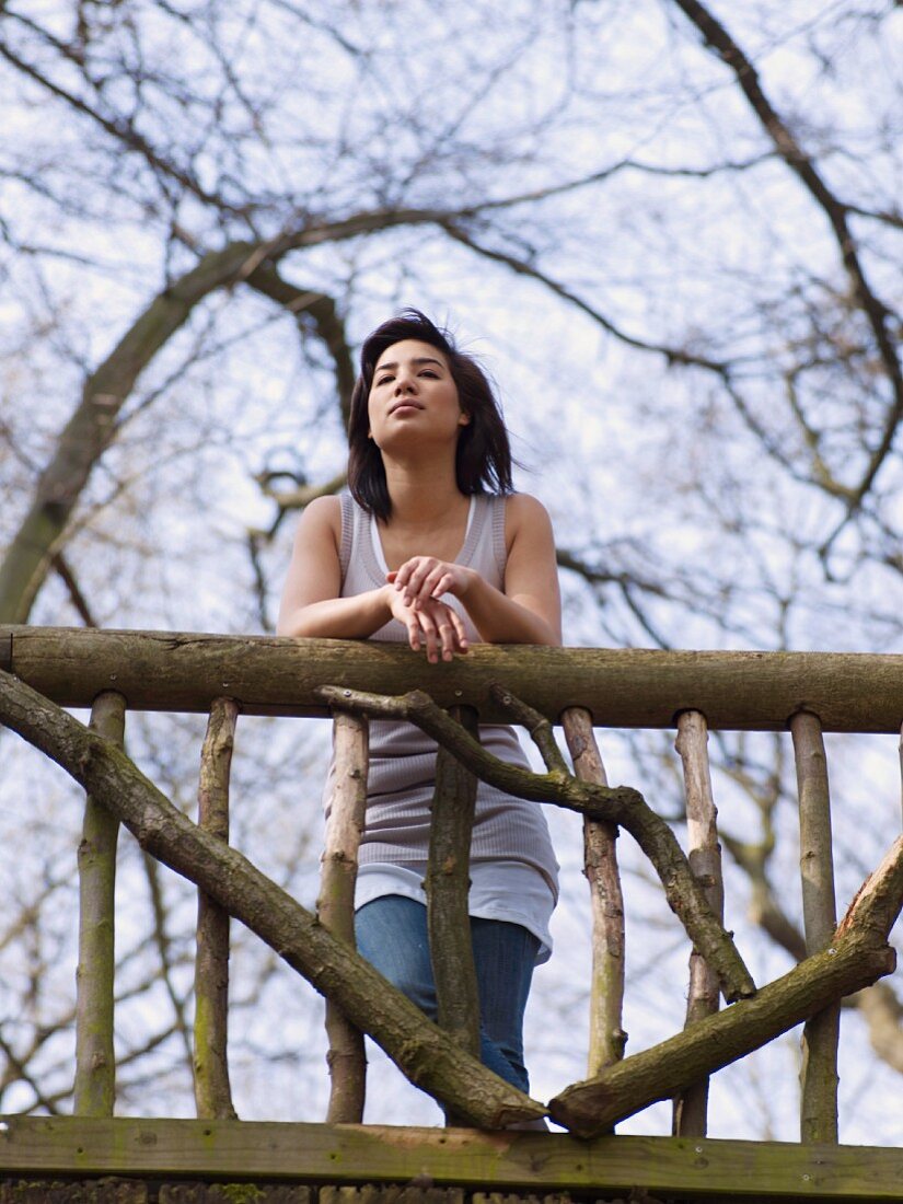 Dark-haired woman standing on wooden bridge