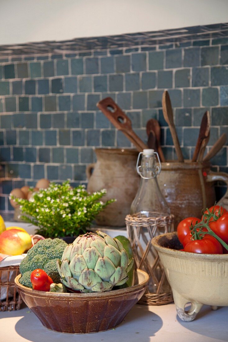 Keramikschalen mit Gemüse auf Küchenarbeitsplatte und gefliester Spritzschutz an Wand