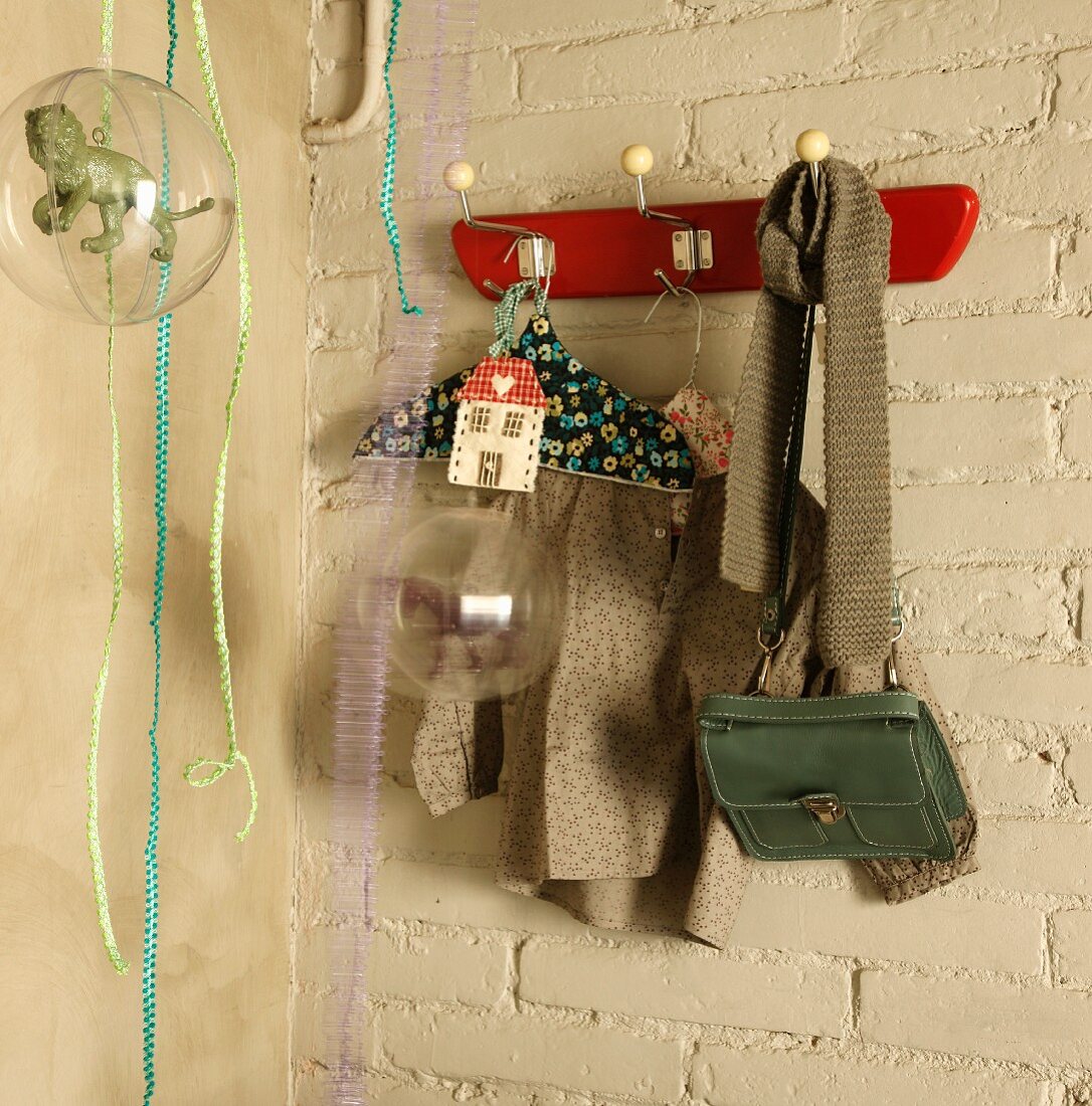 Children's clothing and bag hanging on retro coat rack on whitewashed brick wall