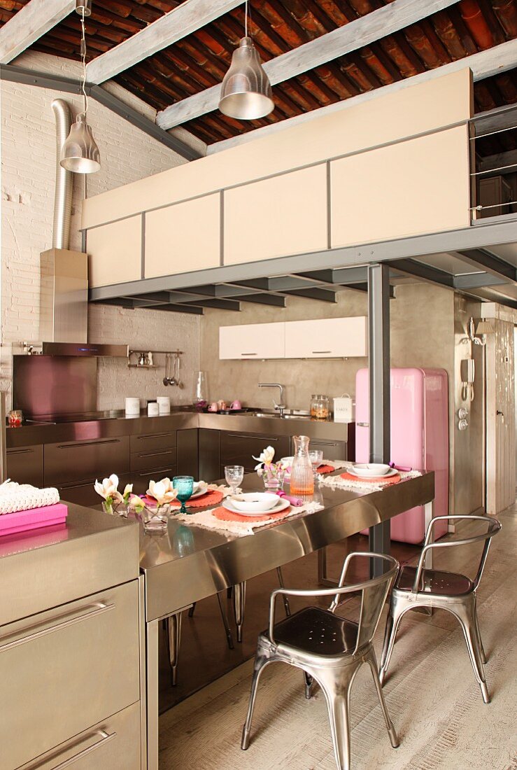 Retro, designer metal chairs at stainless steel counter in open-plan kitchen