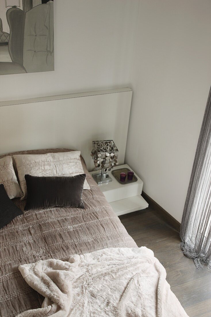 Bedroom in shades of grey with view down onto double bed with headboard and blanket