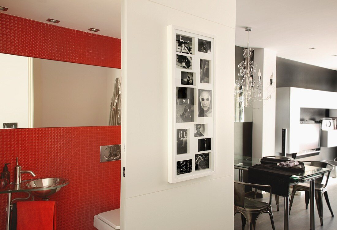 Schwarz-weiße Fotos auf einer Schiebetür vor rot gefliester Gästetoilette, im Hintergrund Ess- und Wohnbereich