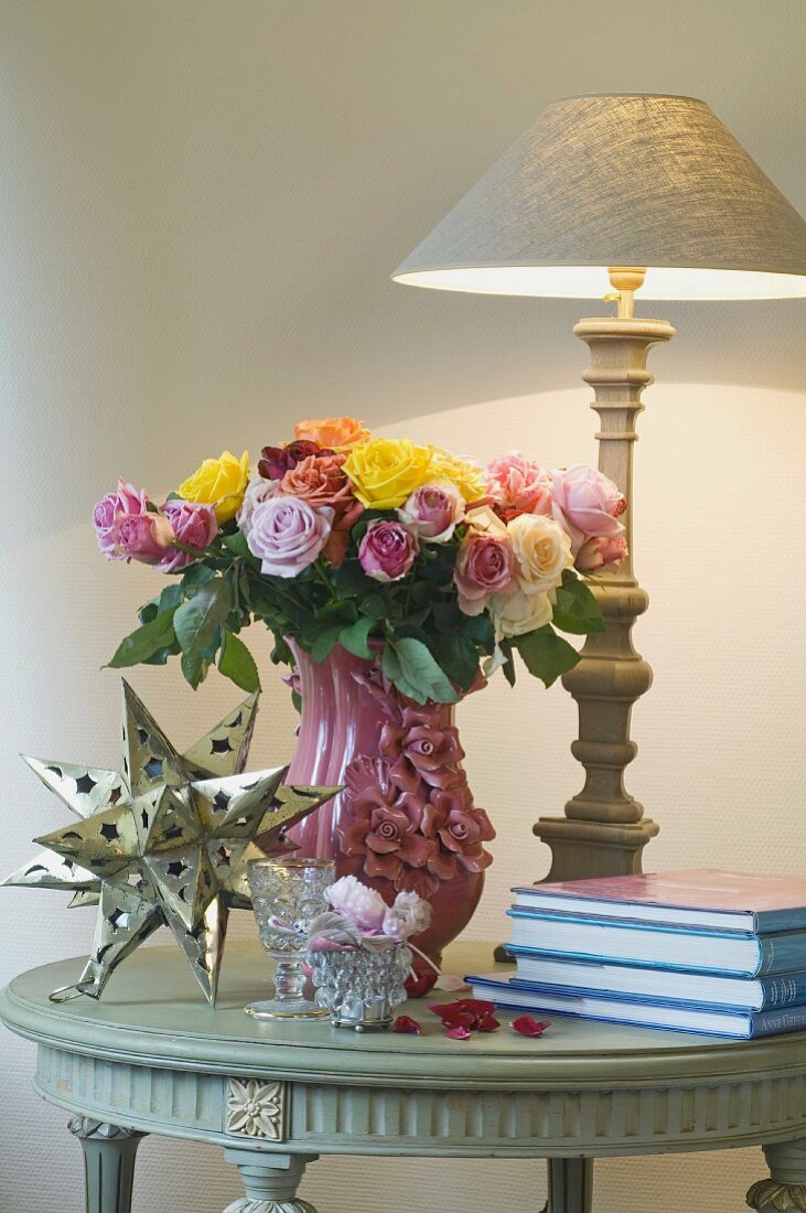Blumenstrauß, Tischlampe, Deko-Stern und Bücher auf einem Tisch