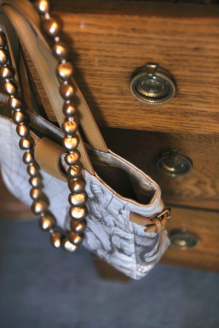 Handbag and necklace hanging at dresser