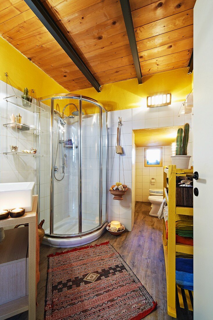 Modernes Bad mit Holzdecke und Duschkabine, davor afrikanischer Teppichläufer auf Parkettboden