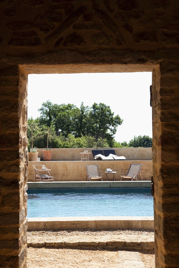 Blick durch Türöffnung auf Pool und Terrassenanlage mit Sonnenliegen