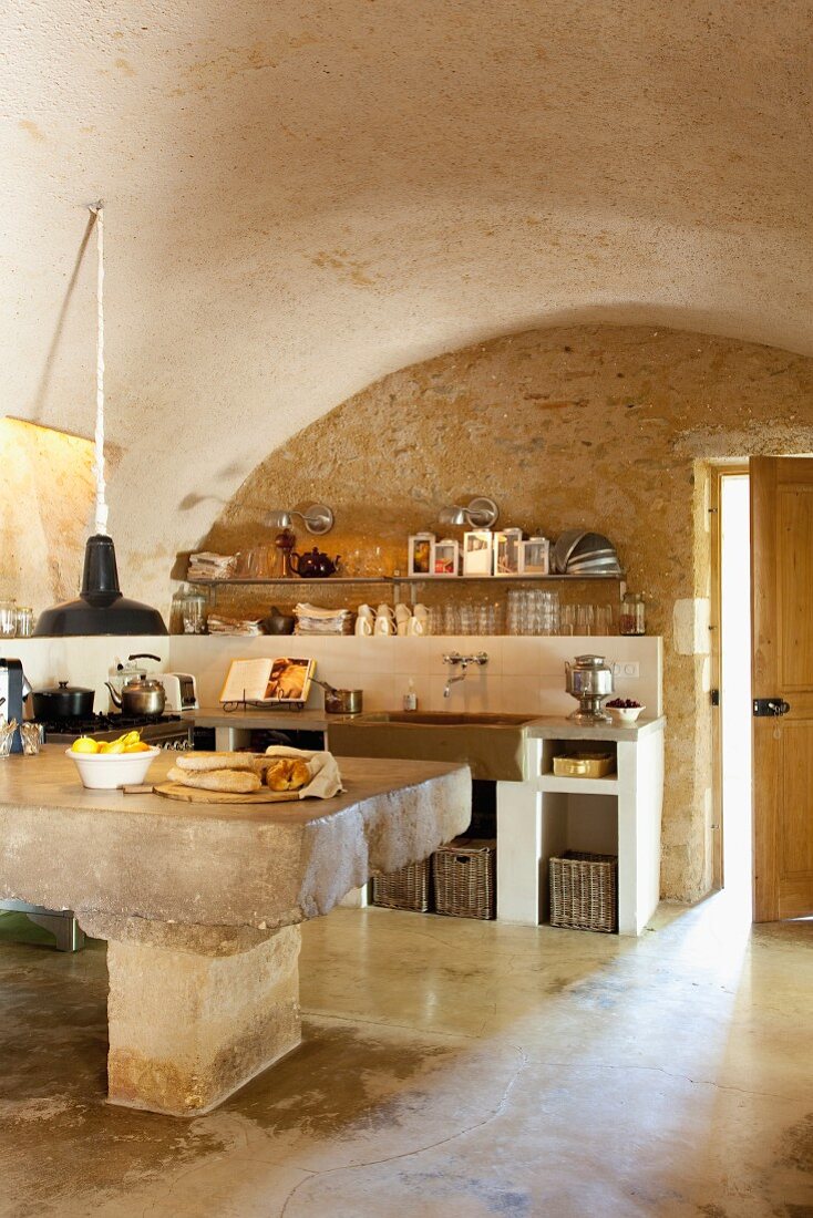 Kitchen table made from massive stone block in rustic kitchen with barrel vault ceiling
