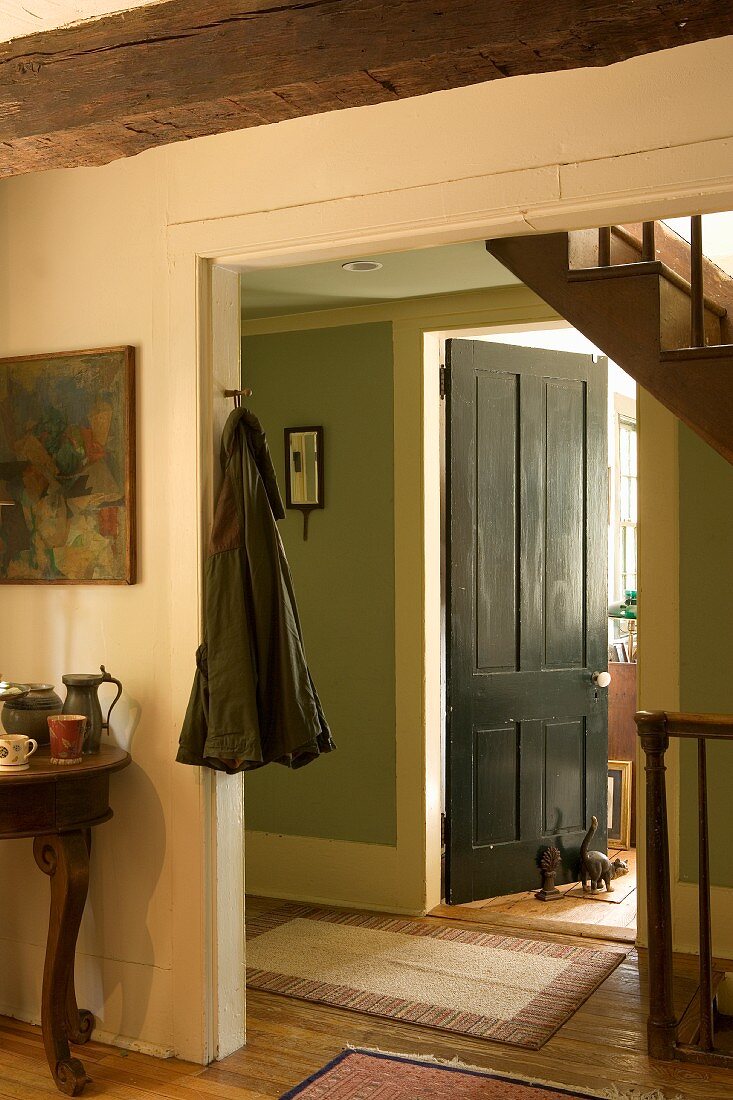 Simple interior in farm house with open doorway and view into foyer with staircase