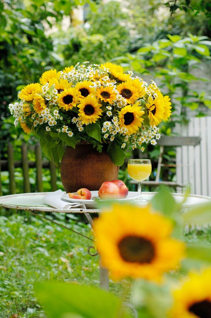 Blumenstrauß und Obst auf Gartentisch